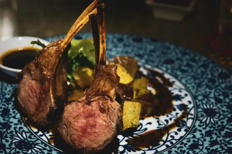 Fine Dining Catering Zürich: Zart rosa gebratenes Lammkarree mit goldener Kruste, knusprigem Gemüse und dunkler Jus, präsentiert auf orientalisch gemustertem Teller von Jane Fine Food