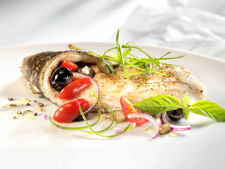 Fine Dining Catering Zürich: Mediterran zubereiteter Fisch mit frischen Kräutern, Cherrytomaten, Oliven und Basilikum, kunstvoll angerichtet von Jane Fine Food
