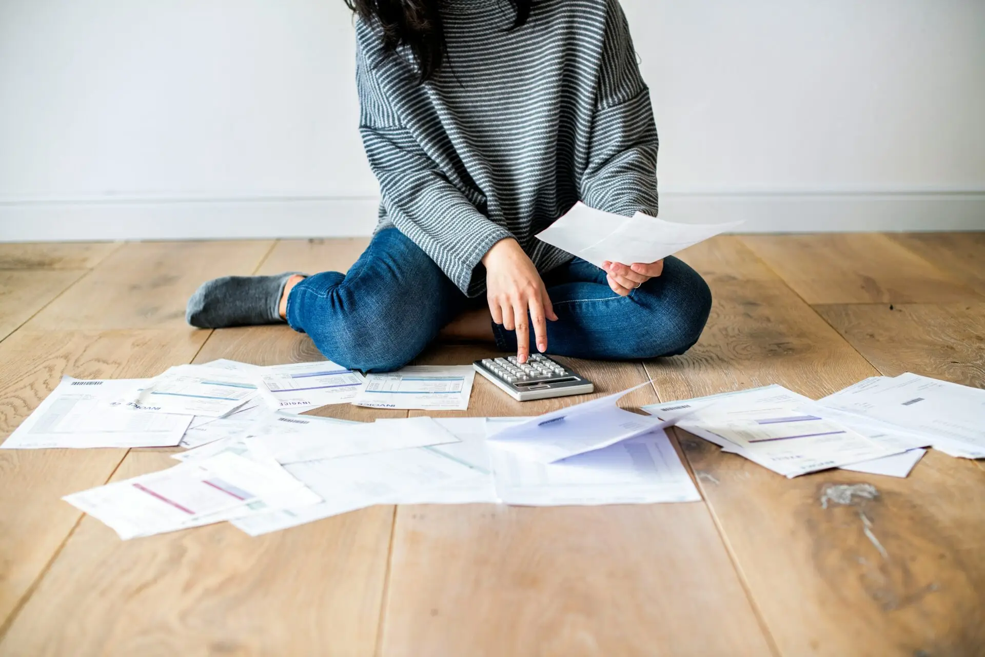 Person arbeitet mit Taschenrechner und Finanzunterlagen
